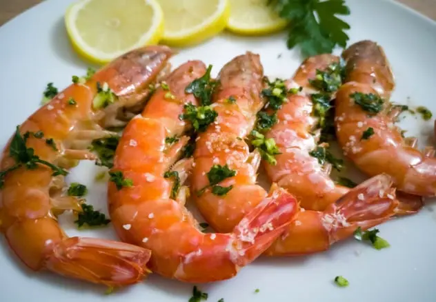 La imagen presenta gambas al ajillo, un plato emblemático de la cocina mediterránea. Preparadas con ajo fresco, perejil y un toque de aceite de oliva virgen extra, las gambas destacan por su sabor intenso y su textura jugosa. Este manjar es perfecto como aperitivo o plato principal, representando la esencia de la gastronomía catalana y su amor por los ingredientes frescos.