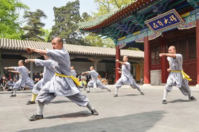 Monjes Shaolin practicando kung-fu en el famoso Templo Shaolin de China. Esta escena muestra un entrenamiento tradicional al aire libre con movimientos sincronizados, destacando la disciplina, el arte marcial y la cultura china. Perfecto para quienes buscan información sobre el kung-fu Shaolin, patrimonio cultural, y destinos turísticos icónicos en China.