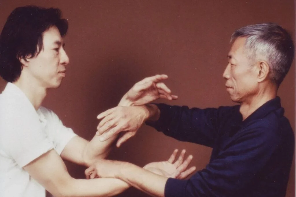 Maestros practicando técnicas tradicionales de Wing Chun, un arte marcial chino enfocado en la defensa personal y el combate cercano. La imagen muestra el entrenamiento mano a mano, destacando la precisión, la técnica y la conexión entre los practicantes. Perfecta para contenido relacionado con las artes marciales chinas, el aprendizaje de Wing Chun y el legado cultural de las técnicas de combate cuerpo a cuerpo.