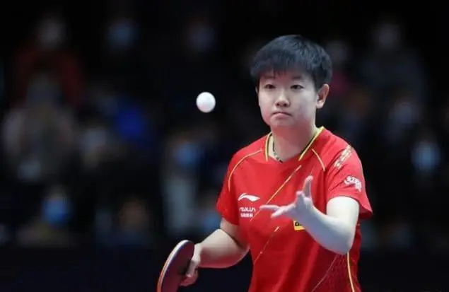 Joven deportista china en acción durante un partido de tenis de mesa, mostrando concentración y técnica en el saque. La imagen destaca la precisión y el enfoque necesarios en este deporte olímpico, popular por su rapidez y habilidades estratégicas. Ideal para contenido sobre tenis de mesa profesional, competiciones internacionales y atletas destacados en deportes de raqueta.