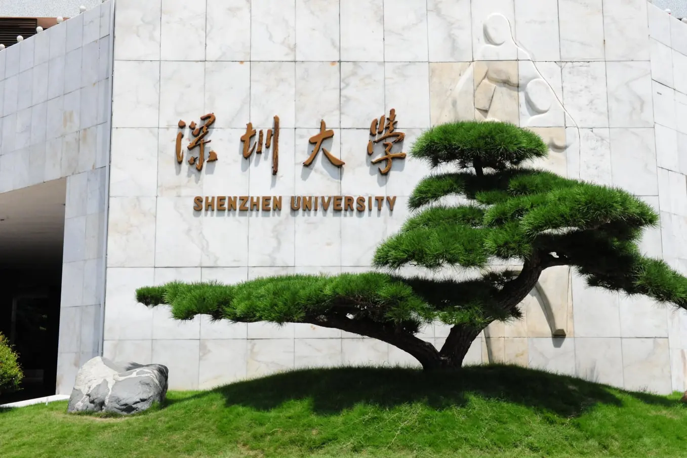 Entrada principal de la Universidad de Shenzhen, símbolo de innovación y desarrollo en una de las ciudades más dinámicas de China. Con un diseño moderno y elementos naturales, refleja el compromiso con la excelencia académica y la sostenibilidad. Reconocida por su enfoque en tecnología, negocios y arte, atrae a estudiantes y académicos de todo el mundo.