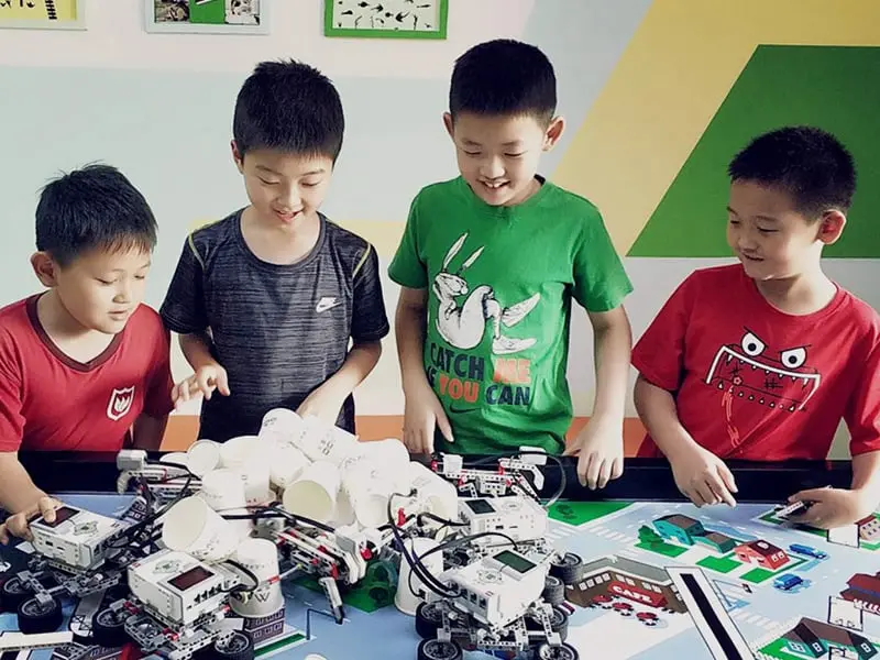 Niños participando en un taller de robótica educativa, diseñando y programando robots en equipo. Esta imagen destaca la importancia de la educación STEM en el desarrollo de habilidades tecnológicas, creatividad y colaboración. Ideal para resaltar el aprendizaje práctico y el fomento del interés por la ciencia y la tecnología desde una edad temprana.