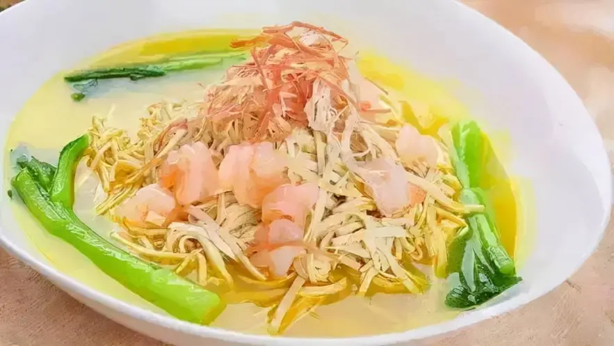 Deliciosa sopa china elaborada con ingredientes frescos como brotes de bambú, gambas y verduras, todo sumergido en un caldo dorado y sabroso. Este plato combina texturas crujientes y suaves, destacando el equilibrio de sabores que caracteriza a la gastronomía china. Ideal para resaltar la riqueza culinaria y la tradición de los platos calientes y reconfortantes.