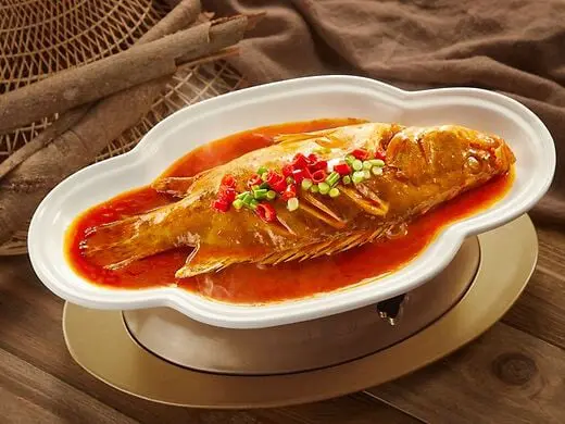 El pescado al vapor en salsa roja es un plato tradicional de la gastronomía china. Este manjar combina pescado fresco cocido al vapor con una salsa picante y ligeramente dulce, adornado con cebollines y chiles. Representa una experiencia culinaria exquisita, ideal para quienes buscan sabores auténticos y saludables, destacando la riqueza de la cocina oriental.