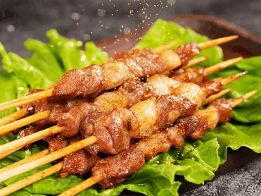 Jugosos pinchos de cordero asados al estilo chino, marinados con una mezcla de especias y ligeramente salpicados de sésamo. Servidos sobre una base de lechuga fresca, estos brochetas son una deliciosa representación de la comida callejera china, perfectos para disfrutar de un bocado lleno de sabor, aroma ahumado y textura tierna y crujiente.