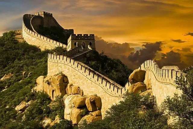 La imagen muestra un tramo icónico de la Gran Muralla China al atardecer, resaltando su impresionante arquitectura y su entorno natural montañoso. Este símbolo de China, Patrimonio de la Humanidad por la UNESCO, es una maravilla histórica y cultural que atrae a millones de visitantes cada año. Ideal para los amantes de la historia, la fotografía y los paisajes únicos.