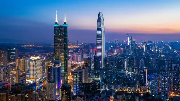 La imagen muestra el impresionante skyline nocturno de Shenzhen, China, con rascacielos iluminados y una vibrante atmósfera urbana. Shenzhen, conocida como el Silicon Valley de China, combina innovación tecnológica con arquitectura moderna. Este destino es ideal para los amantes de las grandes ciudades y la tecnología, ofreciendo una experiencia única en un entorno dinámico y futurista.