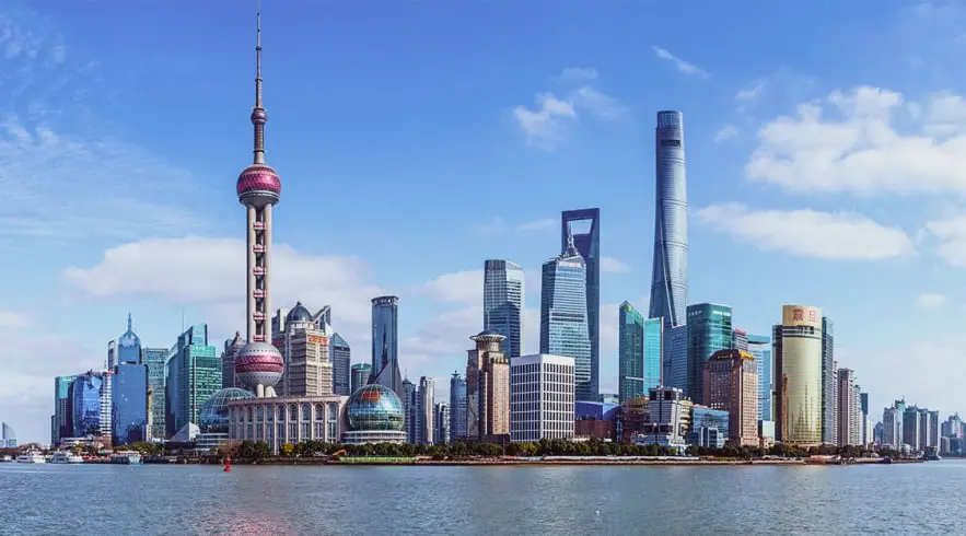 La imagen muestra el icónico skyline de Shanghái, con la Torre Perla Oriental y modernos rascacielos, como el Shanghai Tower. Este vibrante paisaje urbano, junto al río Huangpu, refleja la fusión de tradición y modernidad en China. Ideal para el turismo urbano, Shanghái es un destino imprescindible que ofrece arquitectura futurista, cultura y una vibrante vida nocturna.