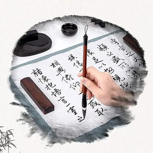 La imagen representa la práctica de la caligrafía china, un arte tradicional que combina escritura y estética. Una mano sostiene un pincel sobre papel de arroz decorado con caracteres caligráficos cuidadosamente trazados. Acompañan elementos esenciales como tinta, tintero y pisapapeles, conocidos como los "Cuatro Tesoros del Estudio". Este arte refleja la profundidad cultural y la armonía entre técnica y expresión artística.