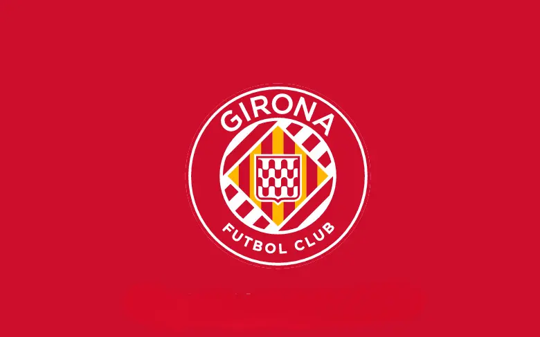 La imagen muestra el escudo oficial del Girona Fútbol Club, un equipo de fútbol español perteneciente a La Liga. El diseño incluye un círculo rojo con detalles en blanco, resaltando una bandera catalana en diagonal y un escudo central con cuadros en blanco y rojo. Es un emblema que refleja el orgullo y la identidad de Girona en el ámbito deportivo.