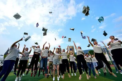 La imagen muestra un grupo de estudiantes chinos celebrando al finalizar el Gaokao, el examen de acceso a la universidad en China, conocido por ser uno de los más exigentes y competitivos del mundo. Los estudiantes lanzan papeles y cuadernos al aire como símbolo de alivio y libertad tras completar esta crucial etapa académica. Este momento refleja la importancia del Gaokao en la vida educativa de los jóvenes en China, un examen que determina en gran medida las oportunidades futuras de los estudiantes para ingresar a las mejores universidades del país. La imagen transmite alegría, esperanza y el sentido de logro de los jóvenes tras superar uno de los mayores retos académicos en China.